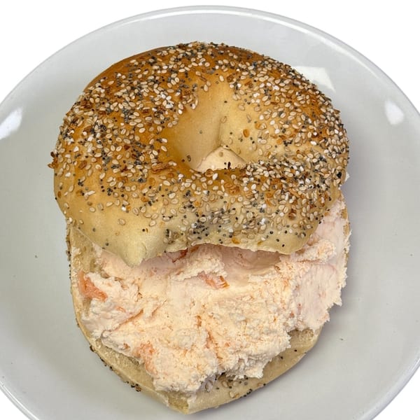 Everything bagel with a generous serving of salmon cream cheese on a white plate.