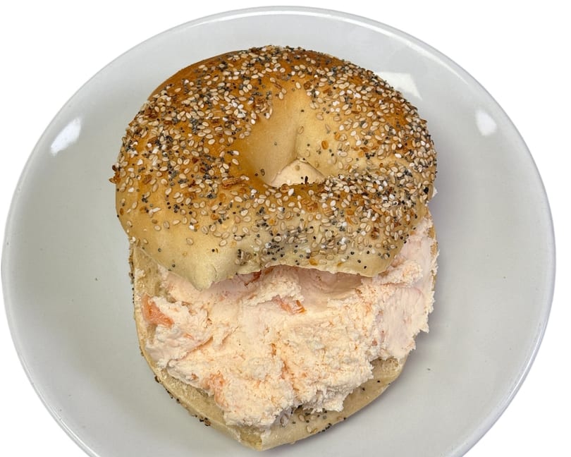 Everything bagel with a generous serving of salmon cream cheese on a white plate.